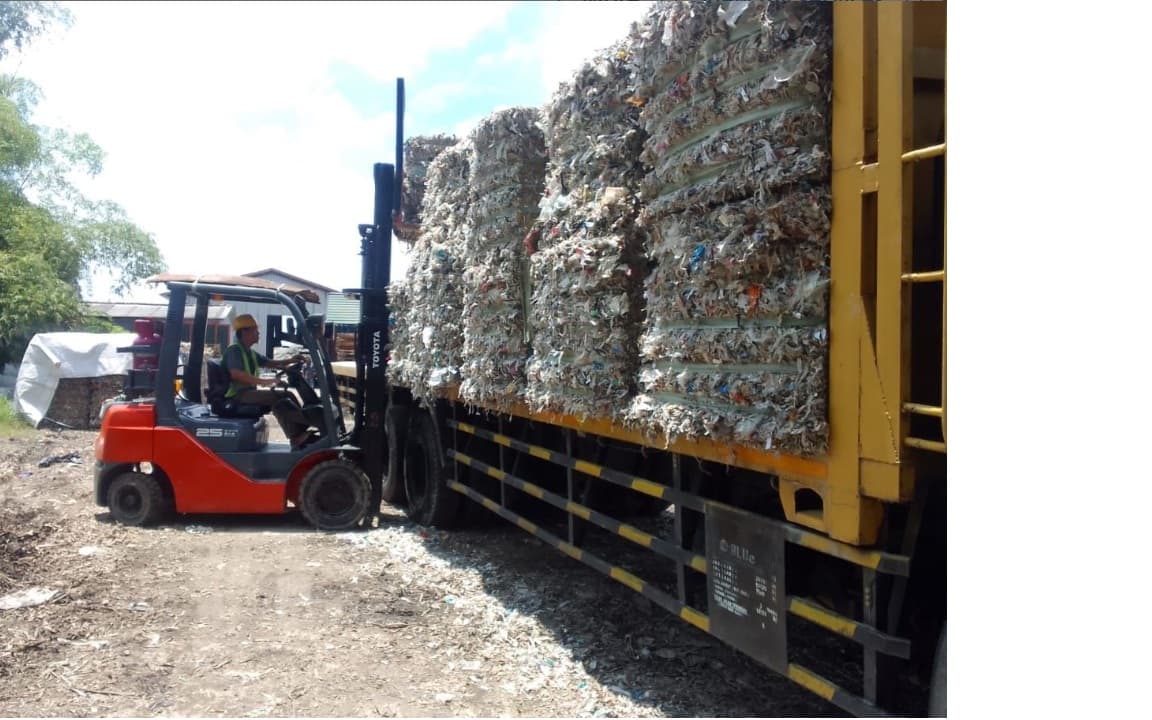 Forklift loading compressed waste bales onto truck at Navasha facility